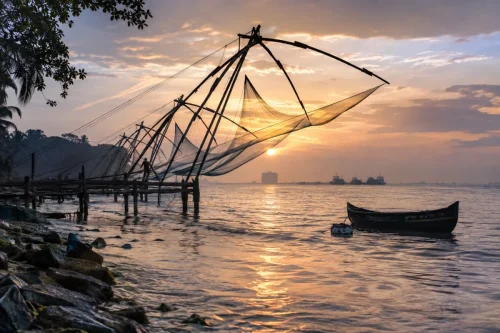 Traditional Chinese fishing nets at Fort Kochi, Kerala, silhouetted against a misty sunrise over the Arabian Sea