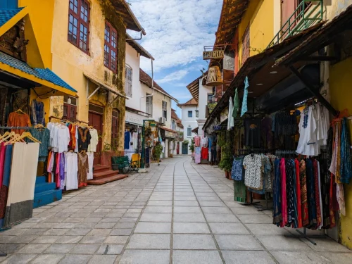 Historic Fort Kochi street lined with colorful colonial buildings, clothing shops, and cafés.